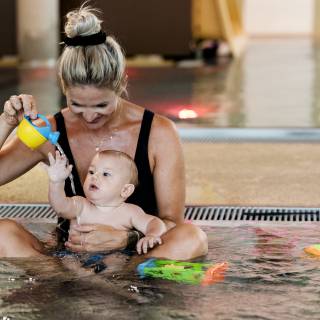 Mutter spielt mit Baby im Pool