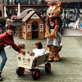 Maskottchen Alpini zieht Kinder im Bollerwagen