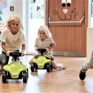Drei Jungs düsen auf Rutschautos durch den Kidsclub