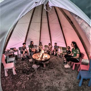 Kinder sitzen am Lagerfeuer im Tipi