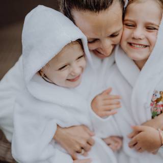 Mama und Kinder kuscheln im Bademantel