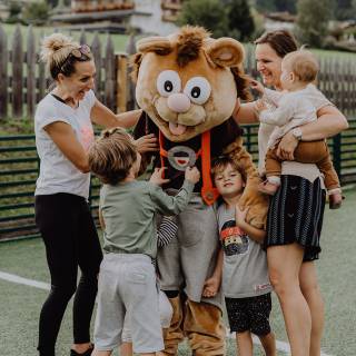 Eltern und Kinder spielen mit dem Maskottchen Alpini