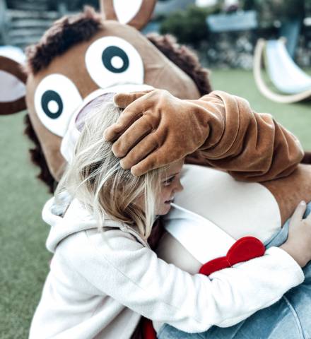 Mädchen kuschelt mit dem Maskottchen Alpini