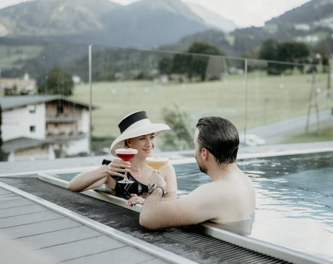 Paar stößt mit Cocktails im Pool an