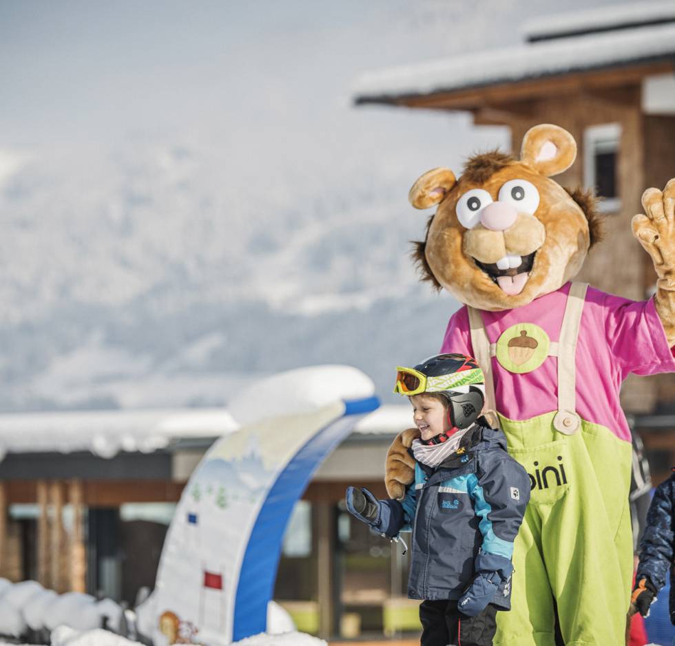 Maskottchen Alpini in der Skischule mit Kinder