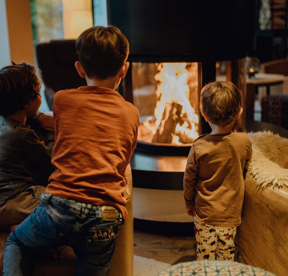 Kinder sitzen vor dem Feuer im Kamin