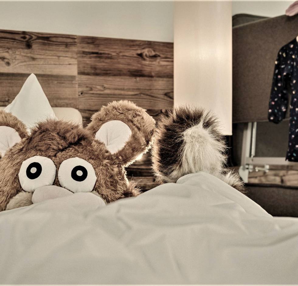 Maskottchen Alpini im Hotelbett