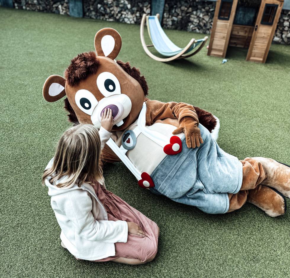 Maskottchen Alpini spielt mit Mädchen